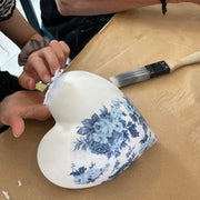 Heart-shaped decorative item with blue floral pattern being decoupaged on.