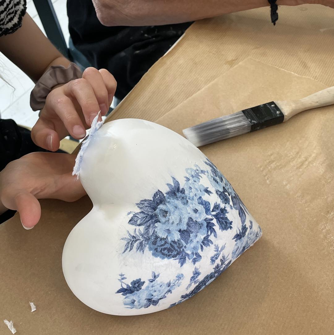 Heart-shaped decorative item with blue floral pattern being decoupaged on.