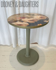 Round wooden table with a floral pattern Romantic Roses decoupage paper, a decoupage paper featuring a printed image of roses in a blue vase, designed for use in furniture art and refurbishment. Chalk painted base in Rubbed Sage premium chalk paint.