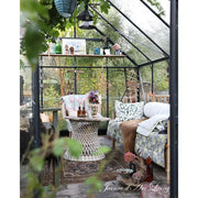 Outdoor patio area with furniture and decor inside a greenhouse.